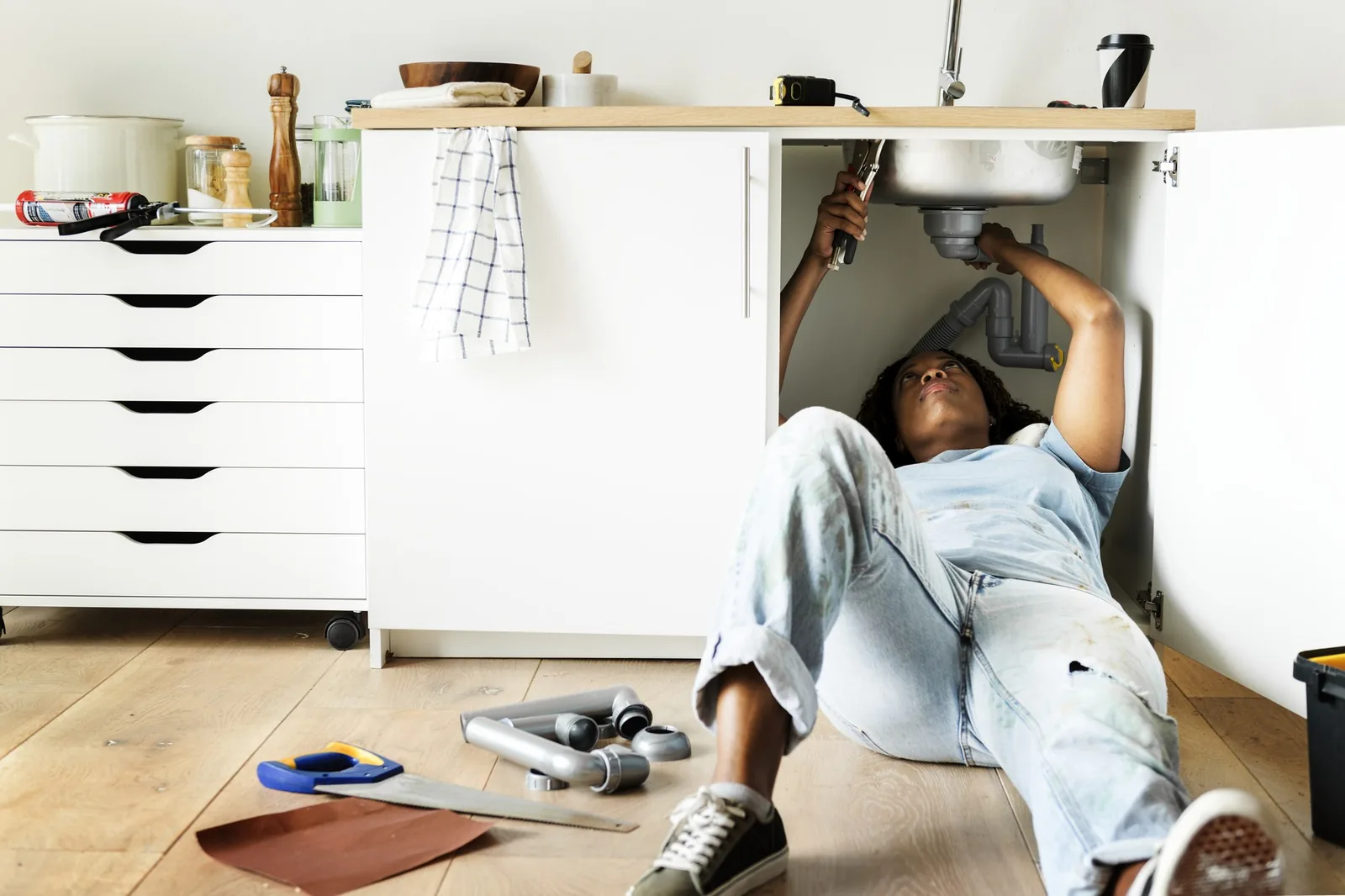 Técnico realizando una reparación bajo el mesón de una cocina